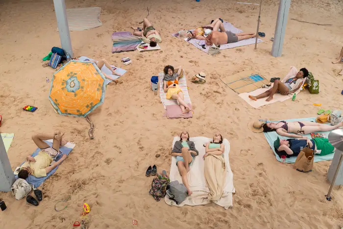 Beach goers lounging on a fake beach inside